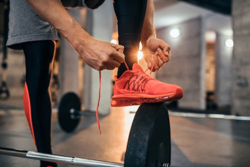 Cropped shot of a man tying his shoelaces at the gym